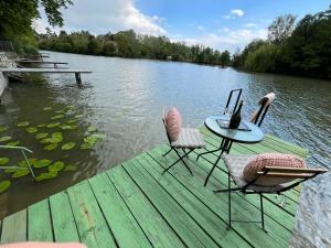 two chairs and a table on a dock on a lake at Szitakötő Békésszentandrás Vendégház in Békésszentandrás