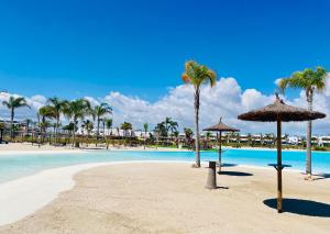 a beach with palm trees and a pool with umbrellas at Villa Almendro Santa Rosalia Lake and Life Resort by PREMIUM SPAIN PROPERTIES in Torre-Pacheco