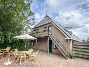a house with a table and chairs and an umbrella at Studio lodge de Bosuil bij Bolmeer Lodges in Zevenhuizen