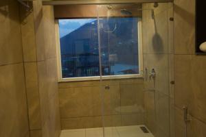a bathroom with a glass shower with a window at Around stays by the Ganges in Rishīkesh