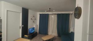 a living room with a blue curtain and a television at Appartement cosy à Chartres avec balcon de 50 m² in Chartres
