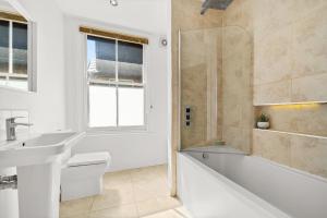 a bathroom with a tub and a sink and a shower at Lovely 4 Bedroom London Home with Free Parking, Garden, WiFi By Roost Accommodation in Kingston upon Thames +38 photos