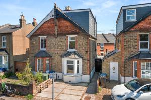 a brick house with a car parked in front of it at Lovely 4 Bedroom London Home with Free Parking, Garden, WiFi By Roost Accommodation in Kingston upon Thames