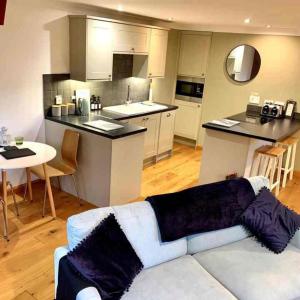 a living room with a white couch and a kitchen at Cysgod Bach & Caban y Saer Cottages in Bala