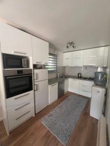 a kitchen with white cabinets and white appliances at Vila sa bazenom Lily in Konjic