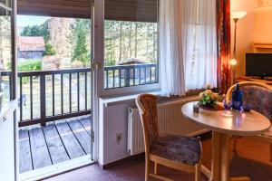 a room with a table and a balcony at Landhotel Lindengarten in Kleinzerlang