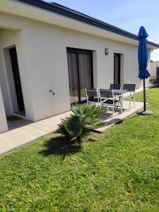 Mours-Saint-EusÃ¨beLa Villa d'A-Mours的庭院配有桌椅和蓝伞。