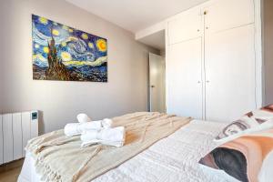 a bedroom with a large bed with a painting on the wall at Apartamento Alguer in L'Ametlla de Mar