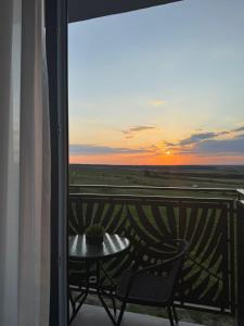 a table and a chair on a balcony with a sunset at Apartament Palace Baile Felix in Baile Felix