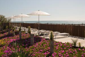 un patio con tavoli, ombrelloni e fiori di Villa Miramar Frontignan a Frontignan Altre 37 foto