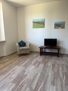 salon z telewizorem, krzesłem i stołem w obiekcie Casalchino-Fattoria La Torre w mieście San Gimignano
