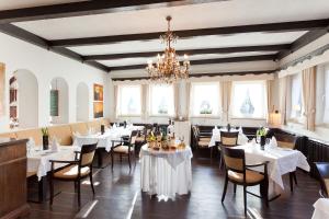 uma sala de jantar com mesas e cadeiras brancas e um lustre em Hotel Kühler Krug em Friburgo em Brisgóvia