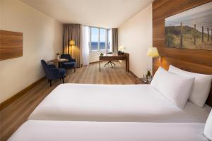 ein Hotelzimmer mit einem großen Bett und einem Schreibtisch in der Unterkunft NH Zandvoort Hotel in Zandvoort