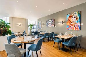 ein Restaurant mit Tischen und Stühlen und einem Gemälde an der Wand in der Unterkunft NH Zandvoort Hotel in Zandvoort