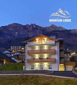 a large white building with a mountain in the background at Mountain Lodge in San Lorenzo in Banale