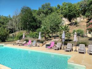 a swimming pool with lounge chairs and umbrellas at Le Séchoir des acacias, Gîte La Noyeraie in Saint-Léon-sur-Vézère