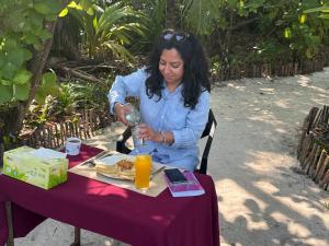 a woman sitting at a table with a plate of food at Skyinn omadhoo in Omadhoo