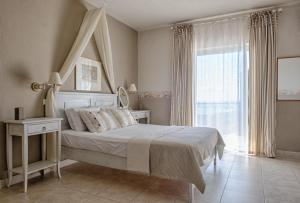 a white bedroom with a bed and a window at Palmina Mare in Paralia Vrachou