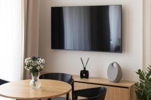 a dining room with a table and a tv on a wall at Six Residences Prague in Prague +17 photos
