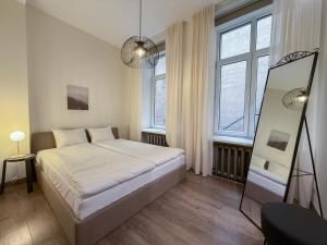 a bedroom with a bed and two windows and a mirror at S13 Old Town Apartments in Riga