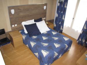 a bedroom with a bed with a blue and white comforter at BreizH HoteL in Crach