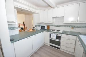a white kitchen with white cabinets and appliances at Margherita in Wroxham