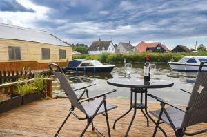 a table and two chairs on a dock with boats at Margherita in Wroxham