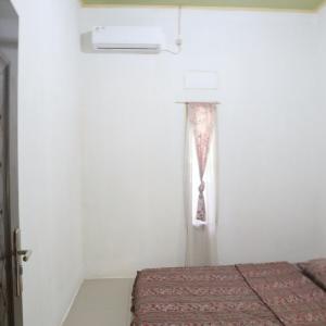 een slaapkamer met een raam met een gordijn aan de muur bij SHYA House in Batukaras