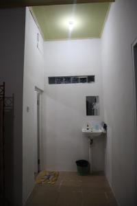 een badkamer met een wastafel en een witte muur bij SHYA House in Batukaras