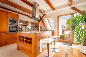 a kitchen with wooden cabinets and a large island with white stools at RJ Apartments Chopina in Sopot