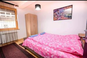 a bedroom with a pink bed and a window at Centar in Vrnjačka Banja
