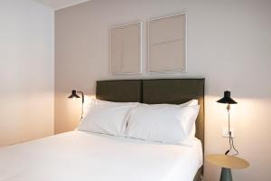 a bedroom with a white bed with two windows at RELSTAY - De Angeli in Milan
