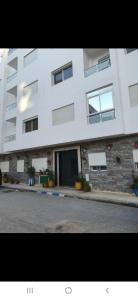 a large white building with windows on a street at Appartement à côté la plage in Oulad Akkou