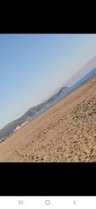 a beach with footprints in the sand and the ocean at Appartement à côté la plage in Oulad Akkou +2 photos