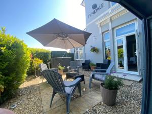a patio with chairs and an umbrella in front of a store at Tyndale Boutique B&B - Adults Only in Torquay
