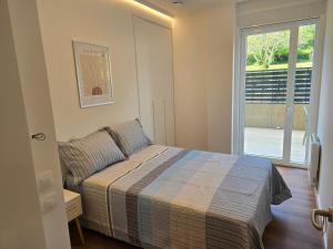a small bedroom with a bed and a window at Piso de lujo con gran terraza in Sanxenxo