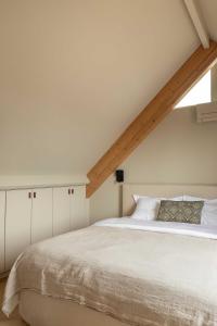 a bedroom with a large white bed with a window at Guesthouse De Waterliefde Loosdrecht in Breukelen