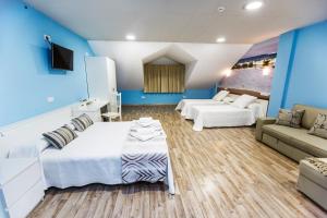 1 dormitorio con paredes azules, 1 cama y 1 sofá en Albergue Arribada, en Muxía