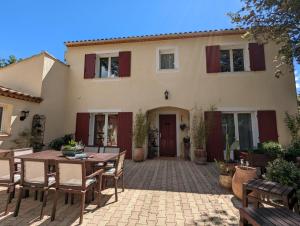 a patio with a table and chairs in front of a house at Les Jardins d'Holi appartement proche Uzès in Garrigues-et-Sainte-Eulalie