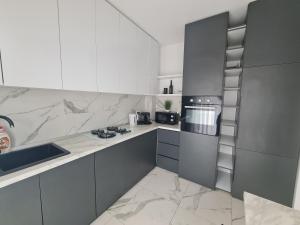 cocina con encimeras de mármol, fregadero y fogones en Glamour, en Oradea