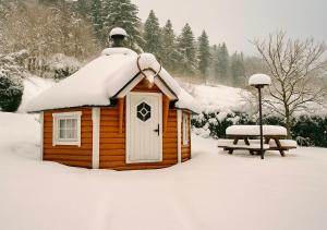 una baita con il tetto coperto di neve e una panchina di Logis Hôtel les Chatelminés a La Bresse