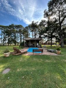 a house with a swimming pool in the grass at Pousada Charqueada Costa do Abolengo in Pelotas