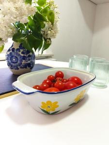 a bowl of tomatoes sitting on a table with a vase at Apartament Warszawska Centrum in Mrągowo +4 photos