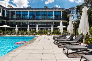 una piscina con sedie e ombrelloni accanto a un edificio di Stegna Deluxe Amber Apartments a Stegna