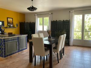 a kitchen with a dining room table and white chairs at Les Jardins d'Holi appartement proche Uzès in Garrigues-et-Sainte-Eulalie