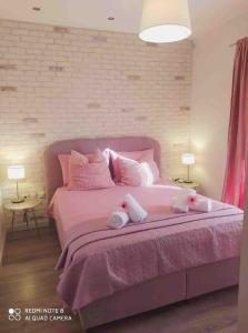 a bedroom with a pink bed with two stuffed animals on it at Luxury mini villas AA in Kríni