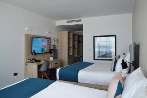 a hotel room with two beds and a desk at be.HOTEL in St. Julianʼs