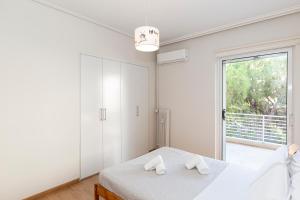 a white bedroom with a bed and a large window at The Glyfada Hideaway in Athens