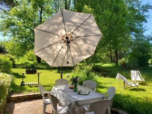 a table and chairs with a white umbrella at Gîte de plain-pied sans escaliers, Dordogne in Firbeix