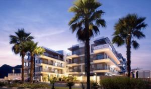 a building with palm trees in front of it at perfect vacation in Eilat - סוויטת בוטיק מעוצבת לחופשה מושלמת באילת במתחם U360 in Eilat